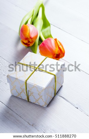 white gift box with tulip flowers on bright wood table