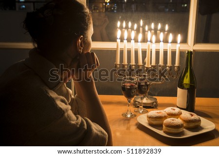 Low key Image of jewish holiday Hanukkah (holiday of lights) with menorah, burning candles, donuts and wine. View to the night Tel Aviv from window