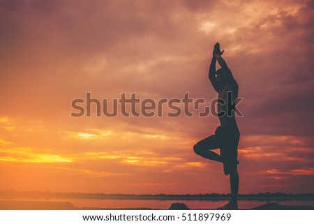 Silhouette of young man doing yoga at sunset.