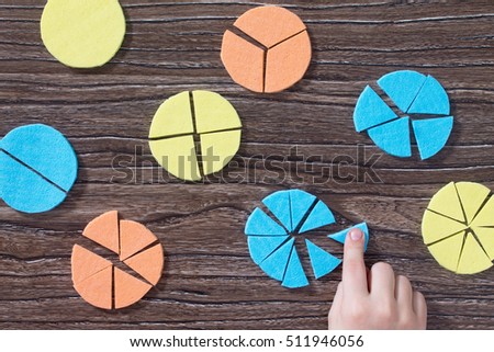 Hand of a child holds missing part of the puzzle in the study of mathematical fraction on a wooden table. Made with his own hands. The concept of early childhood development. Royalty-Free Stock Photo #511946056