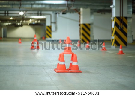 Orange plastic cones in big empty underground parking in stylobate 