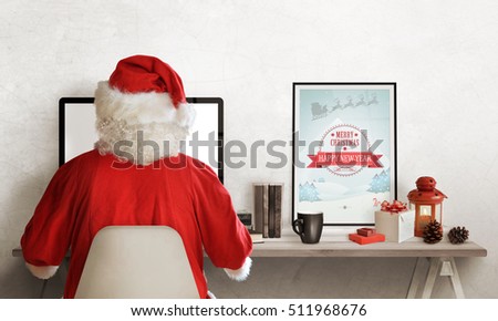 Santa Claus planning trip on computer. Gifts, books, tea, picture and lantern on table.