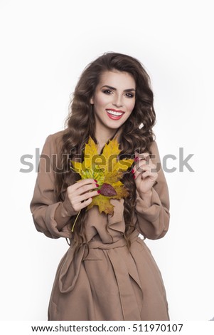 Portrait of cheerful young woman with autumn leafs in front of studio white isolated background