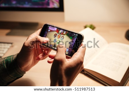 Closeup of man hands playing videogames on cell phone in the evening
