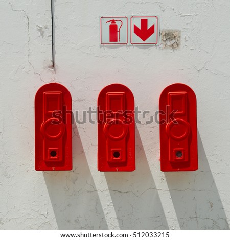Three red extinguisher hanging on old wall