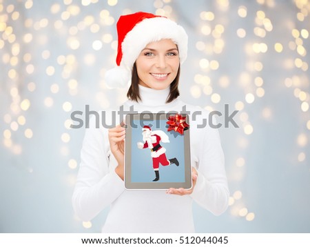 christmas, holidays, technology and people concept - smiling woman holding tablet pc computer with santa claus picture on screen over  lights background