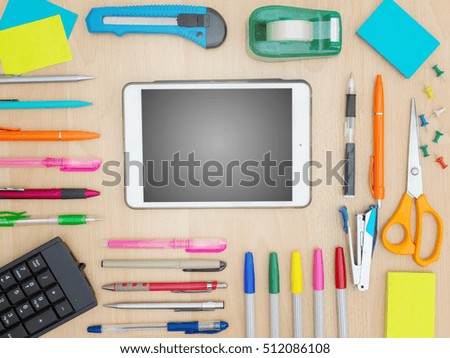 Digital tablet with stationery and office supplies on wooden background