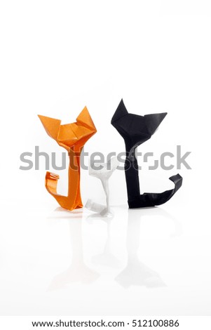 Orange, white and black origami paper cats over a white background. 