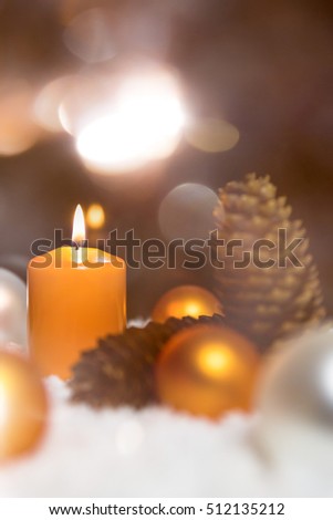 Festive christmas decoration in orange, lightning candles, fir cones and snow on the ground