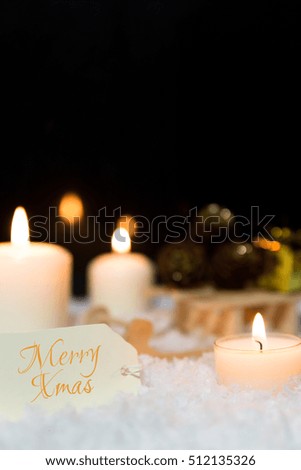 Festive christmas decoration in white, lightning candles, wooden sledge and snow on the ground