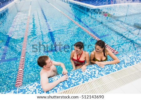 Young adults having fun talking in swimming pool indoors