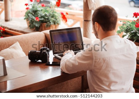 Man is looking at laptop with excitement. Photographer is choosing photos from a shoot