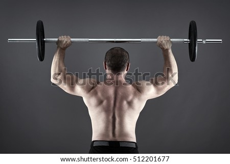 Man doing shoulder workout with barbell on gray background