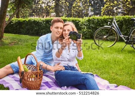 Loving couple doing selfie on a picnic in a park.
