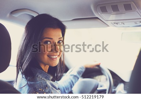 Smiling woman sitting in a car and looking back. Toned image Royalty-Free Stock Photo #512219179