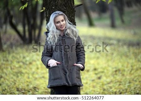 Fashion woman walking in autumn park.  Outdoor fashion photo of young beautiful lady surrounded autumn leaves