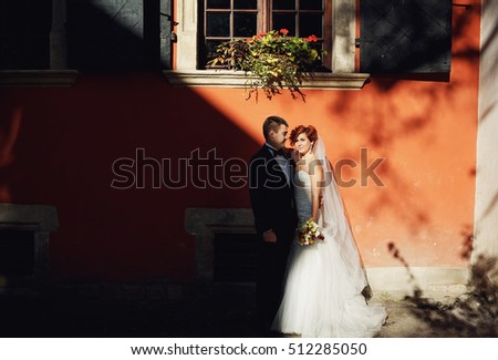 active couple standing against a background of pink house