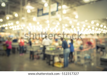 Blur image cashier with line of people at check-out counter. Customers paying with credit card to store clerks, employee bags groceries. Cashier register, checkout payment terminal. Vintage filter.