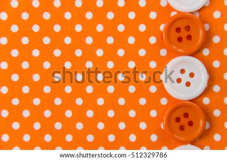 The bright orange fabric in white peas and round plastic buttons, fabric texture, background, place for text