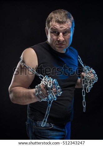 Actor Brutal man with a chain in his hands on a black background.