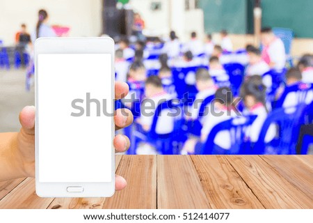 Man use mobile phone, blur image of elementary classroom as background.