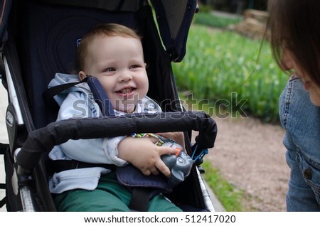 Small baby boy in the carriage in the park with his mother