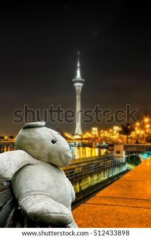 Big white teddy bears sitting on a wooden chair with  Colorful light from the light building in the capital. ASEAN Tourism.