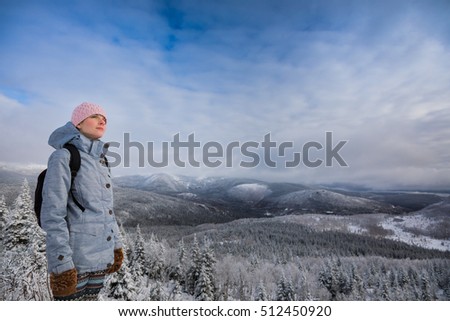 Young Satisfied Woman Looking at the View from the Top of a Mountain in Winter