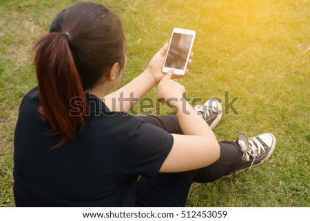 Woman using mobile smart phone in the park.