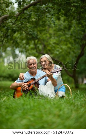 mature couple with guitar   in park