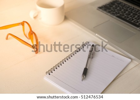 Blank notebook with laptop and pen on wood table. notepad on the laptop and cup on office wooden table