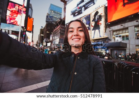 Beautiful young woman tourist taking selfie portrait New York City, Manhattan, Times Square. Multiethnic asian caucasian woman makes photo for her travel blog.