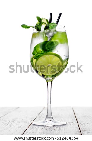 Cocktail in wine glass made with champagne, soda, lime with mint on white background.