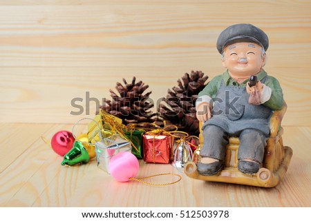 lovely grandparent doll siting rocking bamboo chair with gift boxes and gift decoration christmas on pine wooden background with copy space.