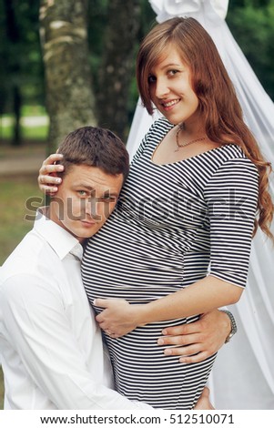 Happy romantic family portrait, husband kneeling and hugging beautiful pregnant wife, waiting for baby concept