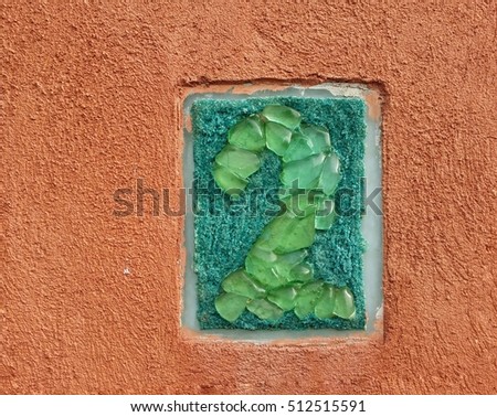 The number two, made from glass pieces, on a building wall
