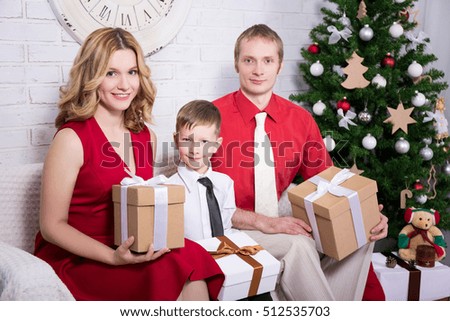 happy young family with gift boxes in front of Christmas tree
