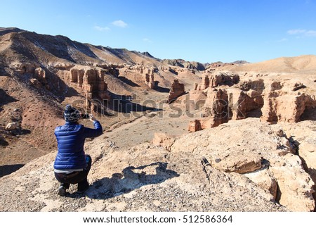 Woman take digital photo on mobile phone in Sharyn Canyon, Kazakhstan
