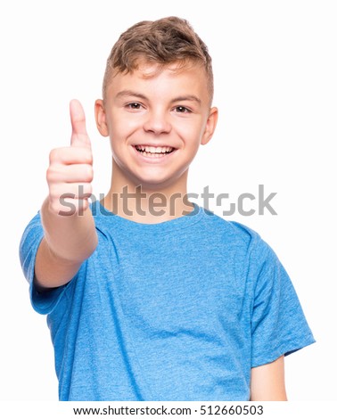 Half-length emotional portrait of caucasian teen boy wearing blue t-shirt. Funny teenager making thumb up gesture, isolated on white background. Handsome child laughing looking very happy.
