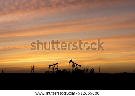 Smoky cloud sunset at blue hour and Silhouette of crude oil pump in the oilfield. 
