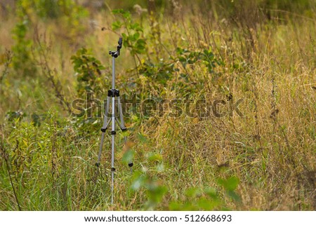 Tripod standing on the field covered with tall grass