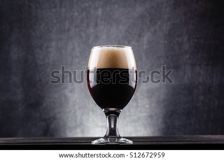 Glass of dark beer over a dark textured wooden background Royalty-Free Stock Photo #512672959