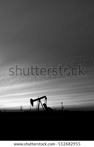 Smoky cloud sunset at blue hour and Silhouette of crude oil pump in the oilfield - black and white 