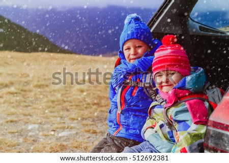 little boy and girl travel by car in winter mountains