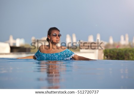 Luxury resort woman relaxing in infinity swimming pool. Summer holidays