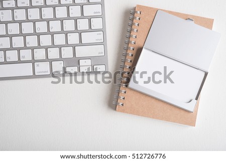 blank name card in case with keyboard and note book on white wooden table