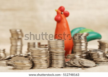 Rooster - a symbol of 2017 year. Plasticine rooster sits among a heap of money. 
