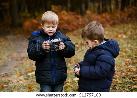 Little boys with an old camera. Adorable little two baby boys. Kids playing in autumn garden