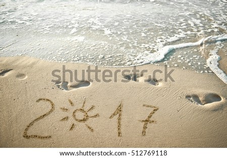 Feet and steps marks on sunny sand beach by sea, summer travel photo, close up footprints in sand, yellow sand with step marks, vacation by sea, summer holiday. New Year 2017 is coming concept