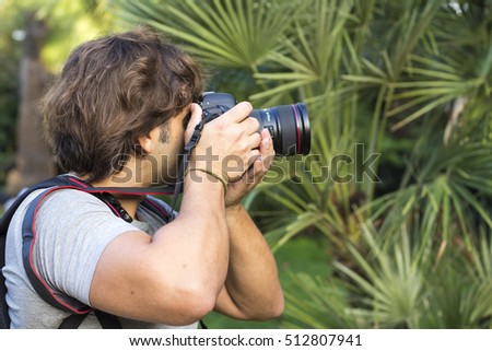 Photographer taking pictures with modern photo camera in forest